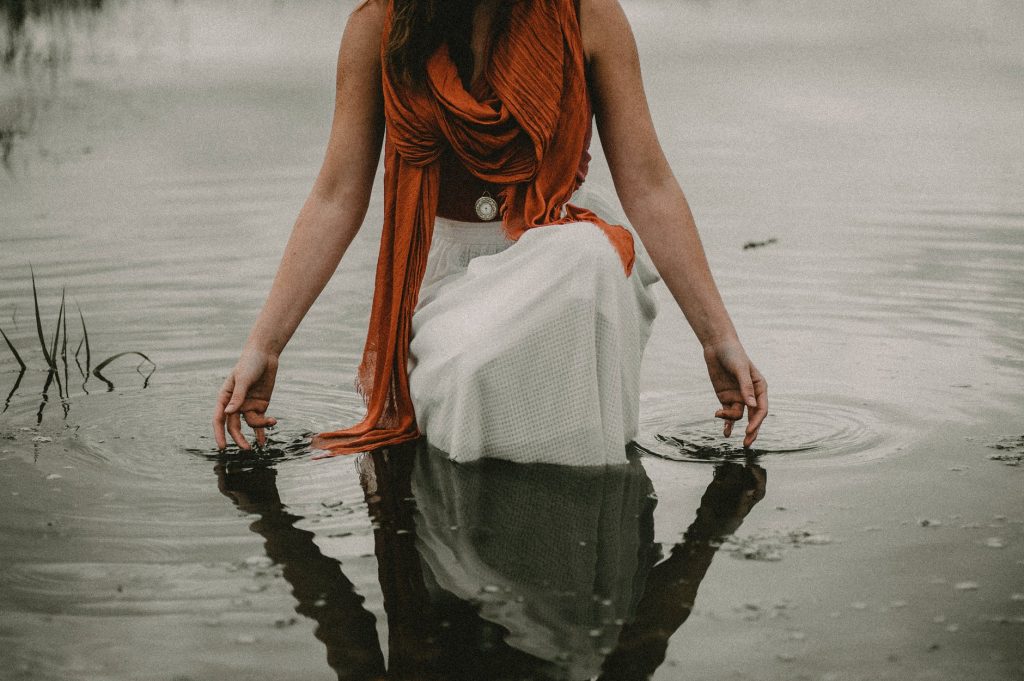 faceless tranquil woman touching water in lake